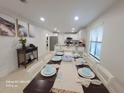 a dining room with a table with plates on it at Stunning 4BD Jacuzzi - 4 Min To Beach Panama City in Panama City Beach