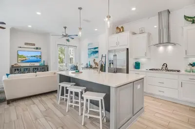 a kitchen with white cabinets and a island with stools at Feeling Tip Sea Golf Cart Bikes Prominence in Watersound Beach