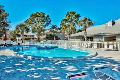 a swimming pool with chairs and a fence at After Dune Delight Pool Tennis Walk To Beach in Seagrove Beach