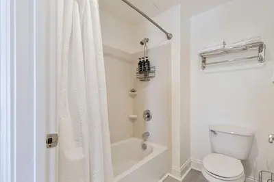 a white bathroom with a toilet and a bath tub at Salt Rim Located In Carillon Beach 4 Pools in Carillon Beach