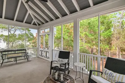 a screened in porch with chairs and a bench at 30A Caspian Blue Carriage in Seacrest