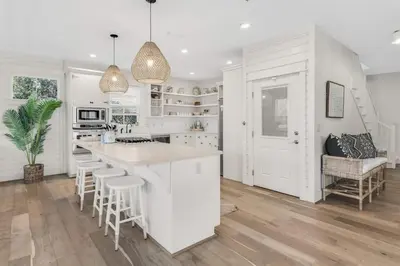 a kitchen with white cabinets and a island with bar stools at Beach Retreat Gulf View Private Beach in Seacrest