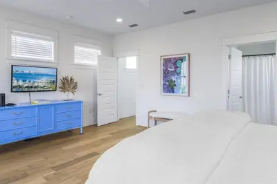 a white bedroom with a blue dresser and a tv at Beach Retreat Gulf View Private Beach in Seacrest