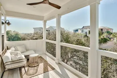 a screened porch with a couch and a ceiling fan at Beach Retreat Gulf View Private Beach in Seacrest