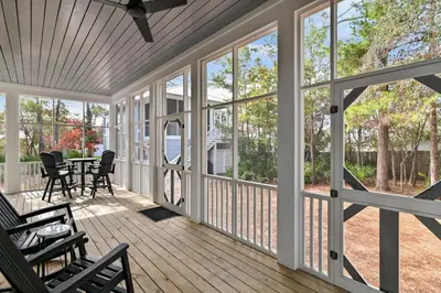 a screened porch with chairs and a table and windows at 30A Caspian Blue Cottage in Seacrest