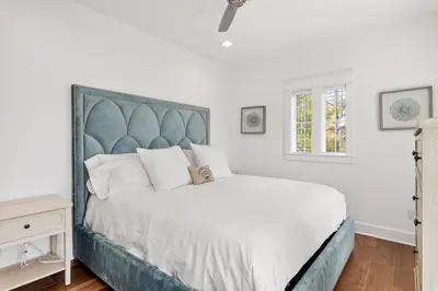 a bedroom with a large bed with a blue headboard at 30A Caspian Blue Cottage in Seacrest