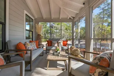 a screened in porch with couches and a table at Goin' Coastal Pet Friendly 6-Seater Golf Cart in Seacrest