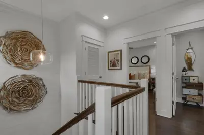a hallway with white walls and a staircase with artwork at Goin' Coastal Pet Friendly 6-Seater Golf Cart in Seacrest