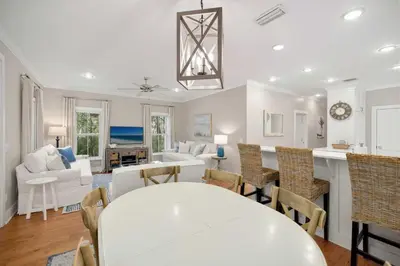 a dining room and living room with a white table and chairs at Driftwood Place Renovations Underway Bikes in Seacrest