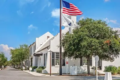 an american flag flying in front of a building at Driftwood Place Renovations Underway Bikes in Seacrest