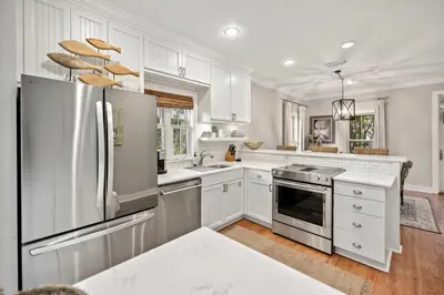 a kitchen with white cabinets and a stainless steel refrigerator at Driftwood Place Renovations Underway Bikes in Seacrest
