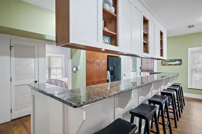 a kitchen with a long counter with stools at Mississippi Magnolia 3 BR 3BA Walk To Beach in Seacrest