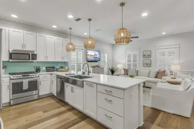 a kitchen with white cabinets and a living room at Southern Tides 4BR 4 5BA Sleeps 14 Golf Cart in Seacrest