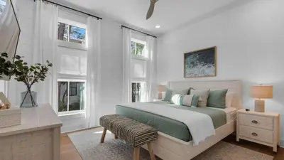 a bedroom with a bed and a table and windows at Vitamin Sea 4BR 4 5BA Golf Cart Pet Friendly in Seacrest