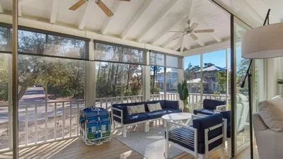 a screened in porch with chairs and a table at Vitamin Sea 4BR 4 5BA Golf Cart Pet Friendly in Seacrest