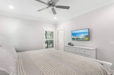 a white bedroom with a bed and a ceiling fan at The Crab House Golf Cart Bikes in Seacrest