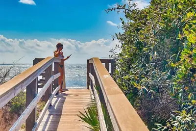 a woman standing on a boardwalk looking at her cell phone at The Crab House Golf Cart Bikes in Seacrest