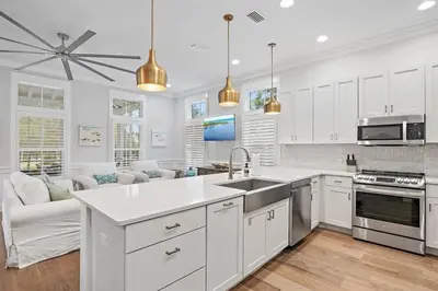 a kitchen with white cabinets and a sink and a couch at The Crab House Golf Cart Bikes in Seacrest