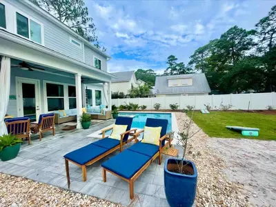 a patio with blue chairs and a swimming pool at Sea Change At Eastern Lake Private Pool in Watersound Beach