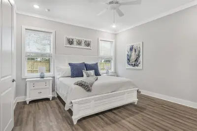 a white bedroom with a bed and two windows at A Wave From It All Bikes Lake Grill in Inlet Beach