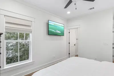 a white bedroom with a bed and a tv on the wall at Shore Me The Way Close To Beach Bikes in Seacrest