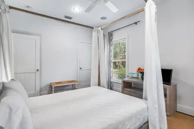 a white bedroom with a bed and a window at The Story House Walk To Beach Pet Friendly in Seacrest