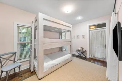 a bedroom with a bunk bed and a chair at The Story House Walk To Beach Pet Friendly in Seacrest