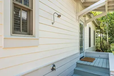 a porch with a window and stairs on a house at The Story House Walk To Beach Pet Friendly in Seacrest