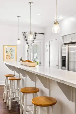 a kitchen with a large white counter and stools at The Story House Walk To Beach Pet Friendly in Seacrest