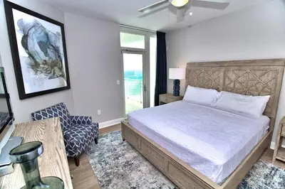 a bedroom with a bed and a chair and a window at Aqua Resort 1111 by Emerald Coast Retreats in Panama City Beach