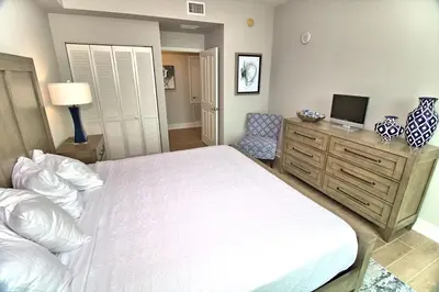 a bedroom with a bed and a dresser with a television at Aqua Resort 1111 by Emerald Coast Retreats in Panama City Beach