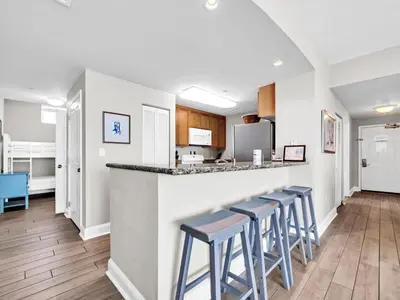 a kitchen with stools at a bar in a room at Aqua Resort 1111 by Emerald Coast Retreats in Panama City Beach