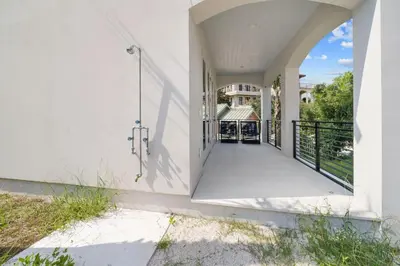 a white house with a balcony with a gate at Big Beach Watch near beach private pool sleeps 21 in Santa Rosa Beach