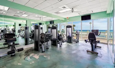 a gym with tread machines and the ocean in the background at Boardwalk 501 in Panama City Beach