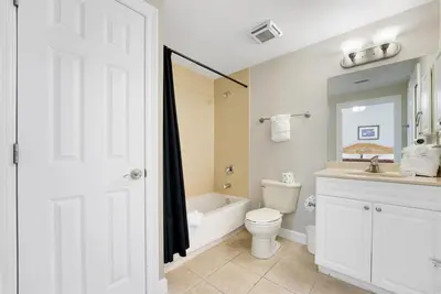 a white bathroom with a toilet and a sink at Boardwalk 501 in Panama City Beach