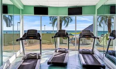 a gym with three treadmills in front of the ocean at Boardwalk 501 in Panama City Beach