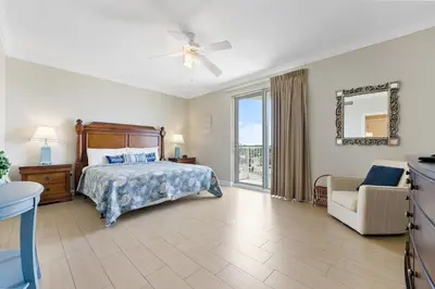 a bedroom with a bed and a chair and a window at Boardwalk 501 in Panama City Beach