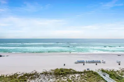 a beach with chairs and the ocean in the background at Twin Palms 603 in Panama City Beach