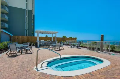a hot tub on a patio with tables and chairs at Twin Palms 603 in Panama City Beach