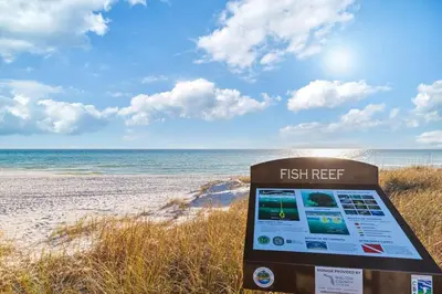 a sign on a beach with the ocean in the background at New Pool 5 Bedroom Screened Porch in Inlet Beach
