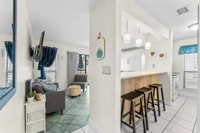 a kitchen and living room with a bar and stools at Endless Summer #D1 in Panama City Beach