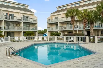 a swimming pool in front of a building with palm trees at Endless Summer #D1 in Panama City Beach