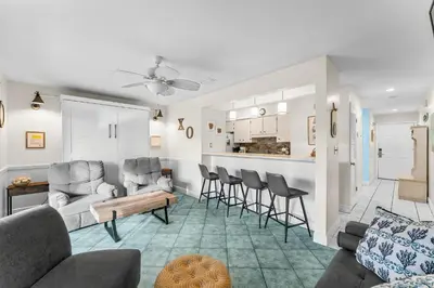 a living room with a couch and chairs and a kitchen at Endless Summer #D1 in Panama City Beach