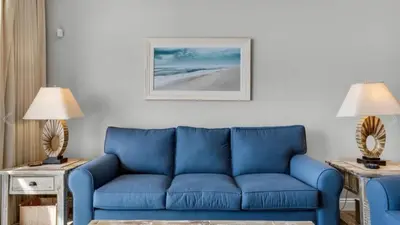 a blue couch in a living room with two lamps at Calypso 402E by Warren Beach Rentals in Panama City Beach