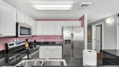 a kitchen with white cabinets and a stainless steel refrigerator at Calypso 402E by Warren Beach Rentals in Panama City Beach