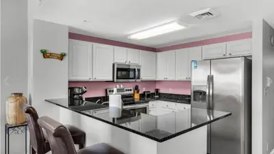 a kitchen with white cabinets and a stainless steel refrigerator at Calypso 402E by Warren Beach Rentals in Panama City Beach