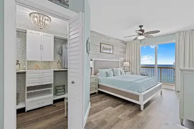 a white bedroom with a bed and a balcony at Calypso 1204E in Panama City Beach