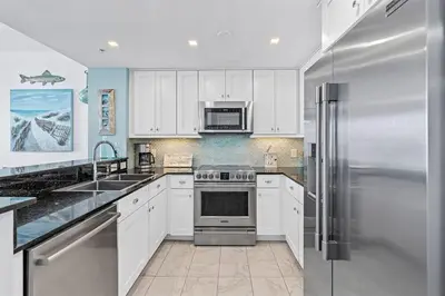 a kitchen with white cabinets and a stainless steel refrigerator at Calypso 1204E in Panama City Beach