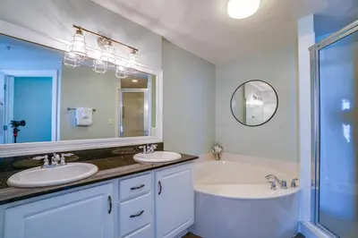 a bathroom with two sinks and a tub and a mirror at Calypso 1401E in Panama City Beach