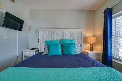 a bedroom with a blue bed with blue pillows at Calypso 1401E in Panama City Beach